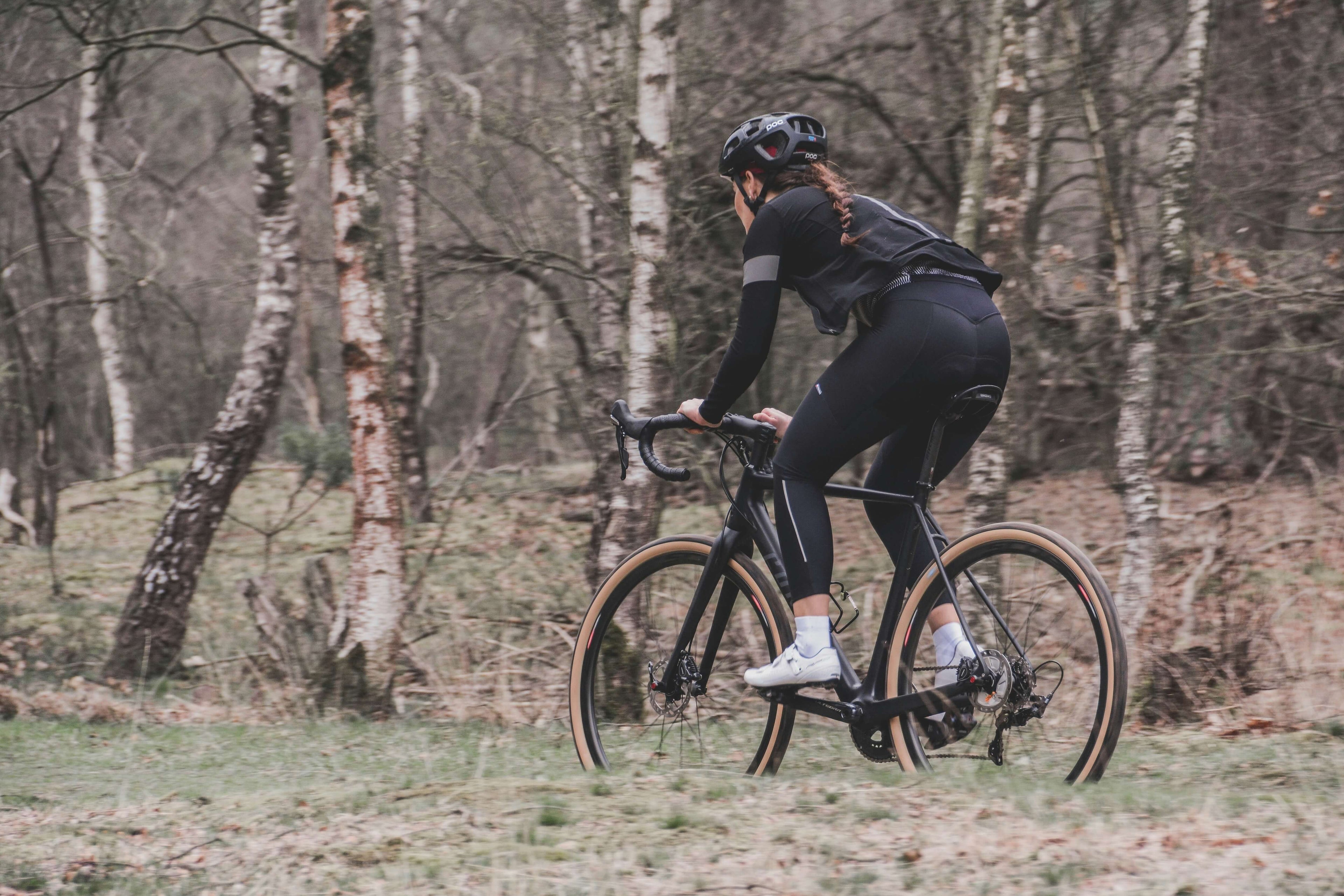Image of a woman riding a gravel bike through the woods
